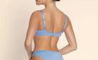 Woman wearing a blue bikini against a beige background
