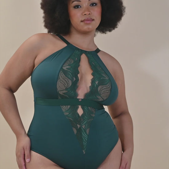 Full-figured African American woman lounges in an emerald green lace bodysuit