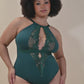 Full-figured African American woman lounges in an emerald green lace bodysuit