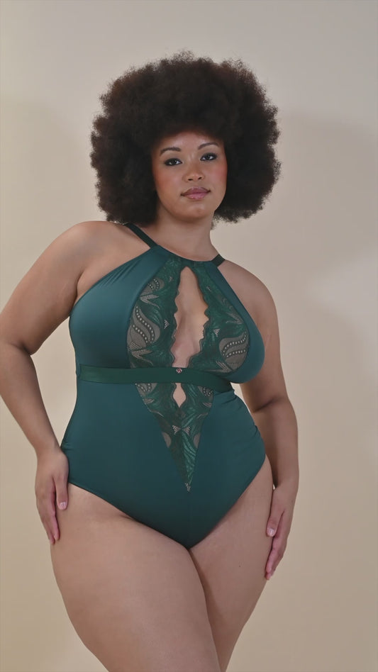 Full-figured African American woman lounges in an emerald green lace bodysuit