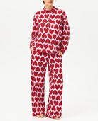 Person wearing a red heart-patterned pajama set on a white background