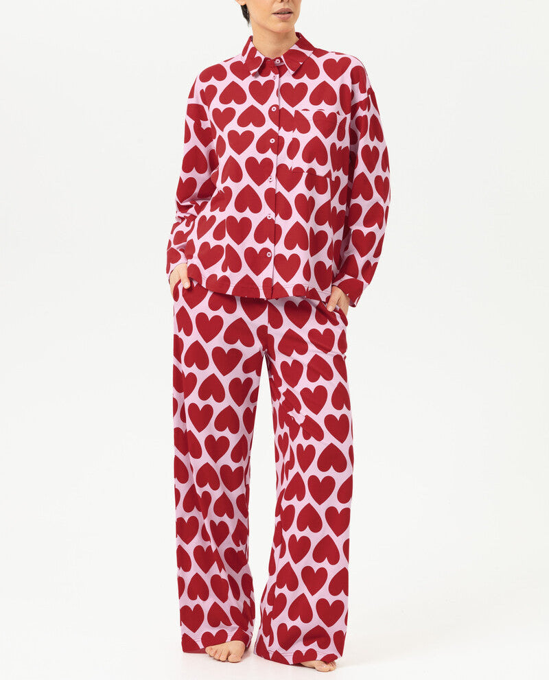 Person wearing a red heart-patterned pajama set on a white background