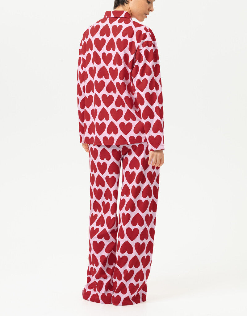 Person wearing red heart-patterned pajamas on a white background
