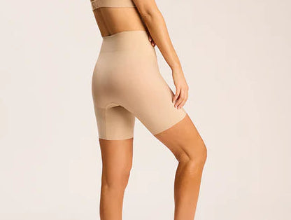 Woman wearing a beige shapewear outfit on a plain background